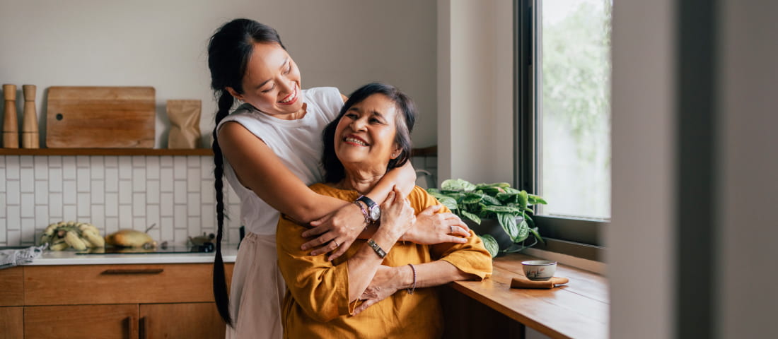 Dos mujeres adultas abrazándose en su cocina platicando sobre su futuro.