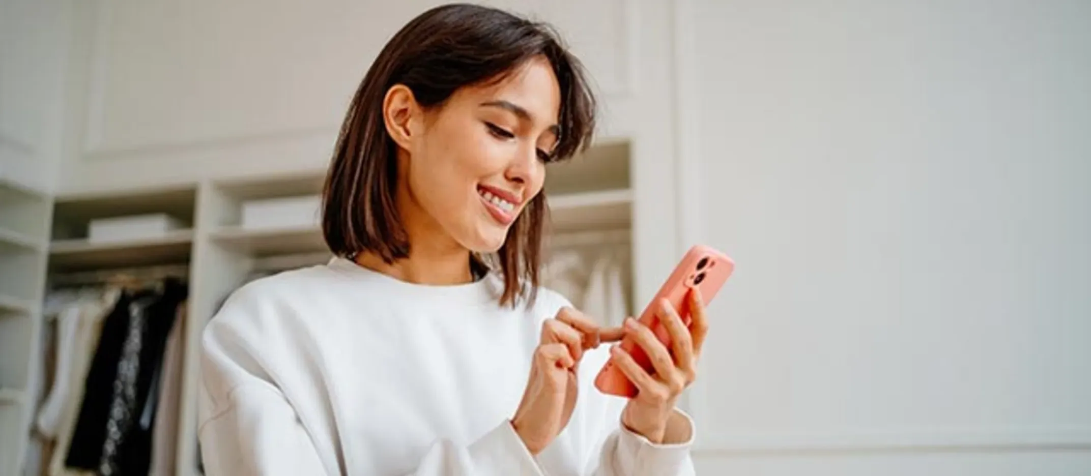 Persona usando un teléfono móvil en un espacio interior iluminado, representando la gestión de una cuenta digital y operaciones bancarias desde una aplicación.