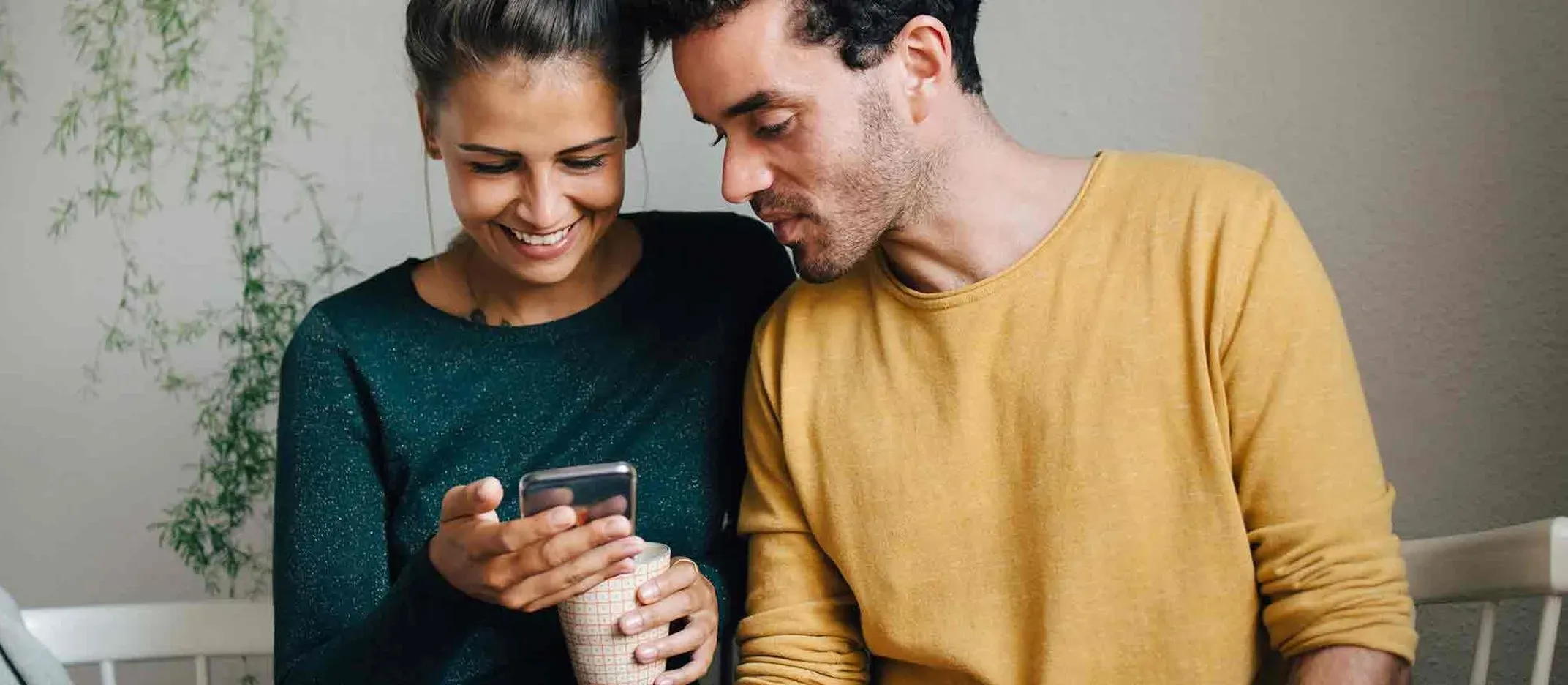 Pareja revisando funciones útiles de su app bancaria desde el celular en casa.