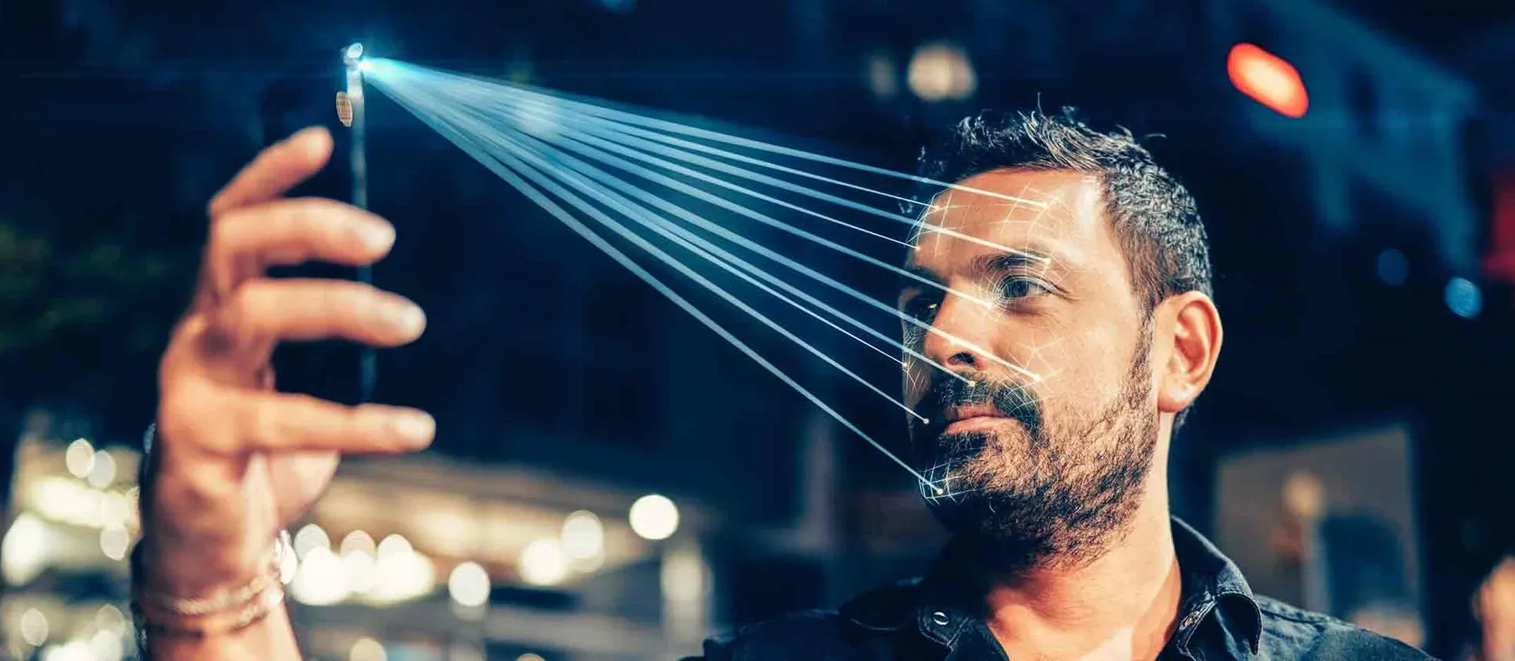 Teléfono móvil proyectando líneas de luz hacia el rostro para escaneo facial, tecnología biométrica para autenticación segura.