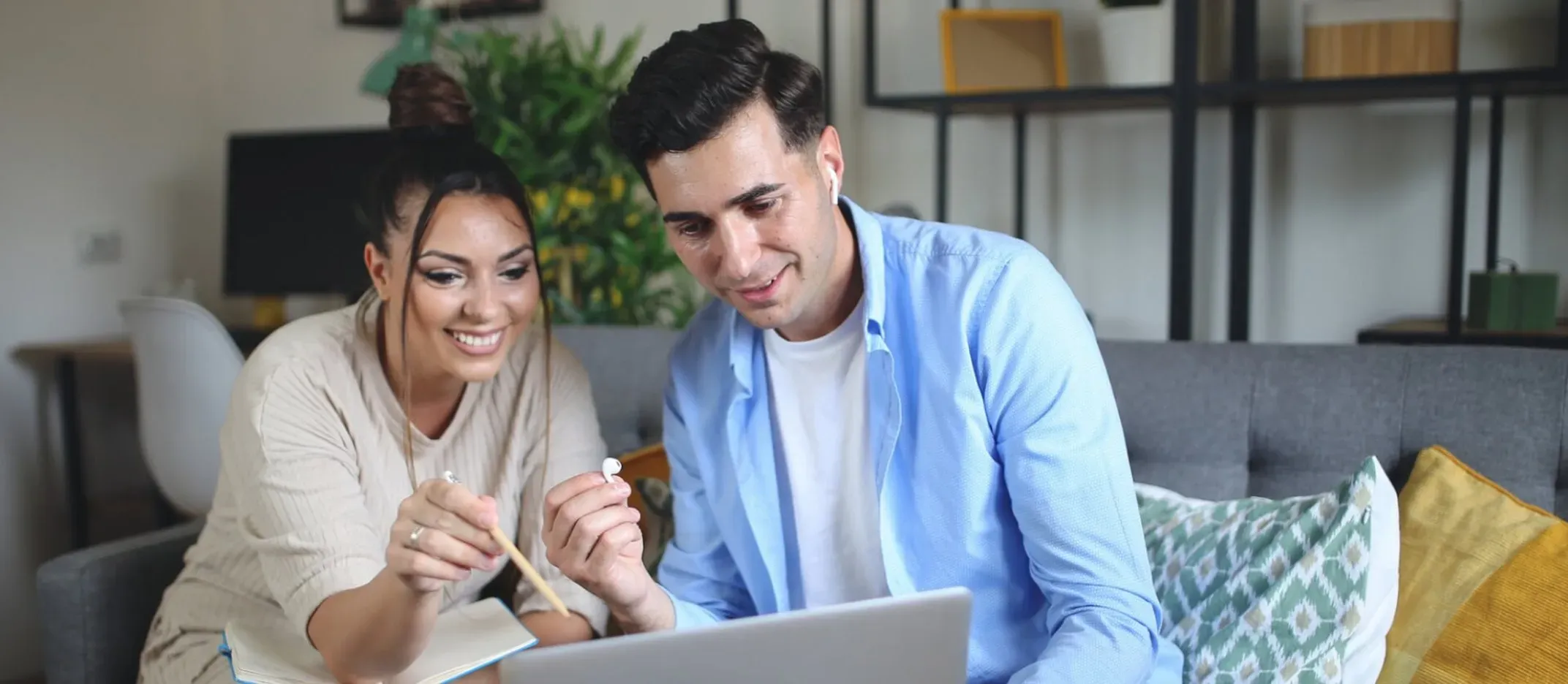 Pareja revisando información en una laptop en la sala para calcular el valor de su casa.