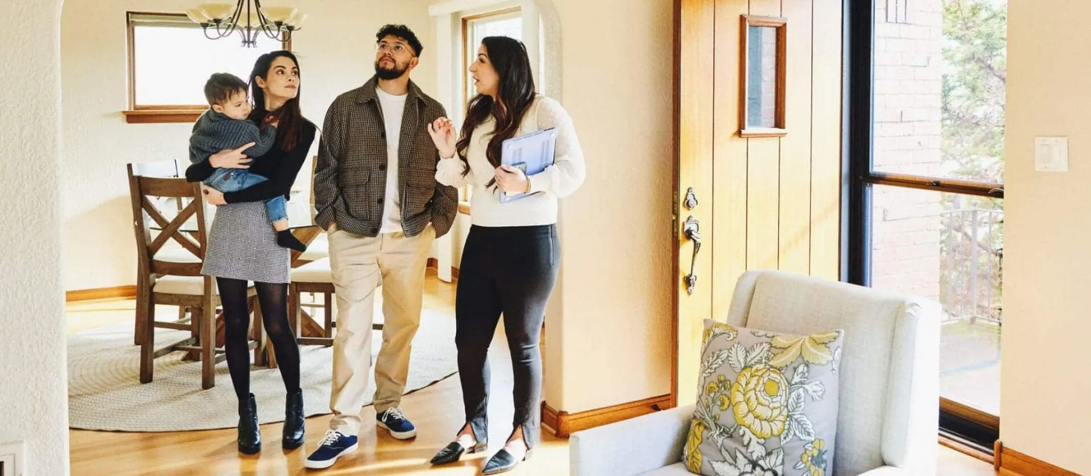 Familia visitando una casa en venta con agente inmobiliario en el interior del hogar.