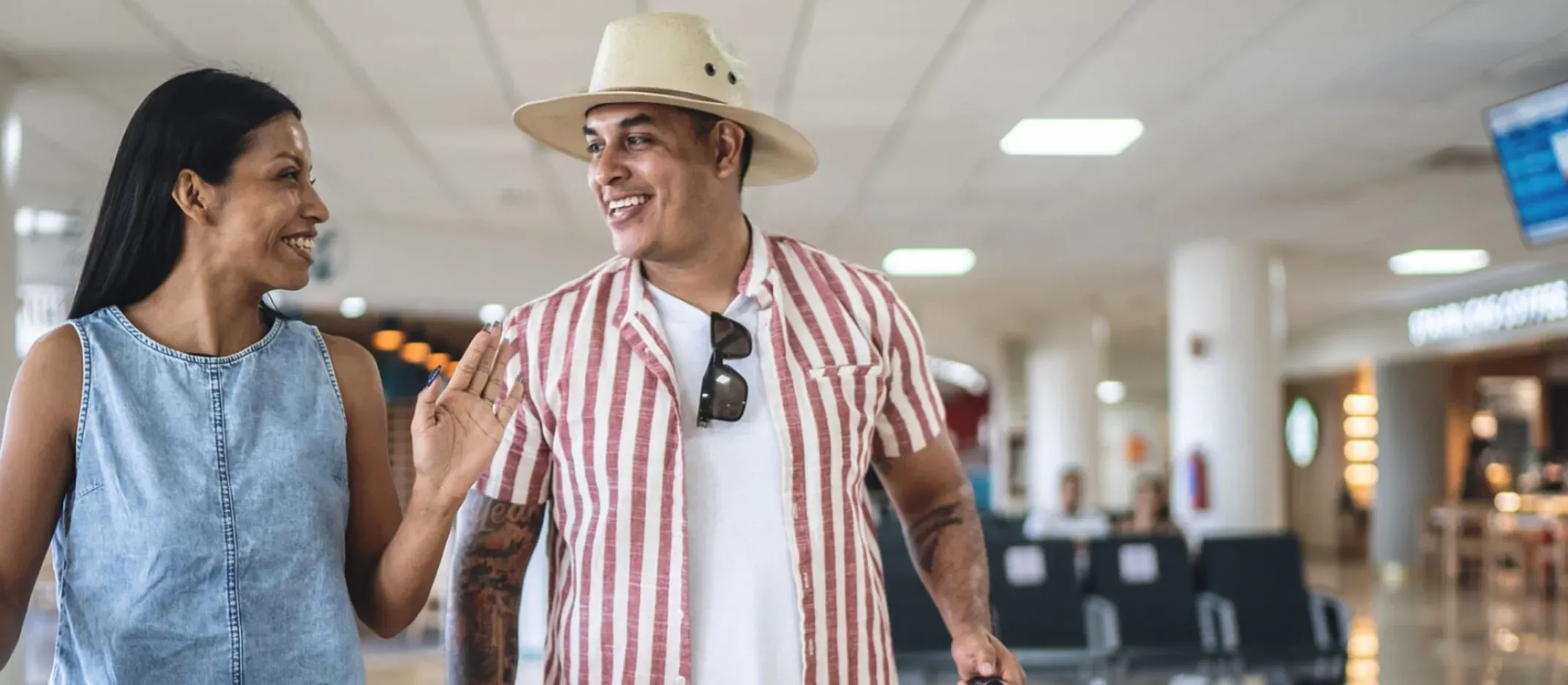 Pareja caminando en un aeropuerto con maletas durante sus vacaciones.