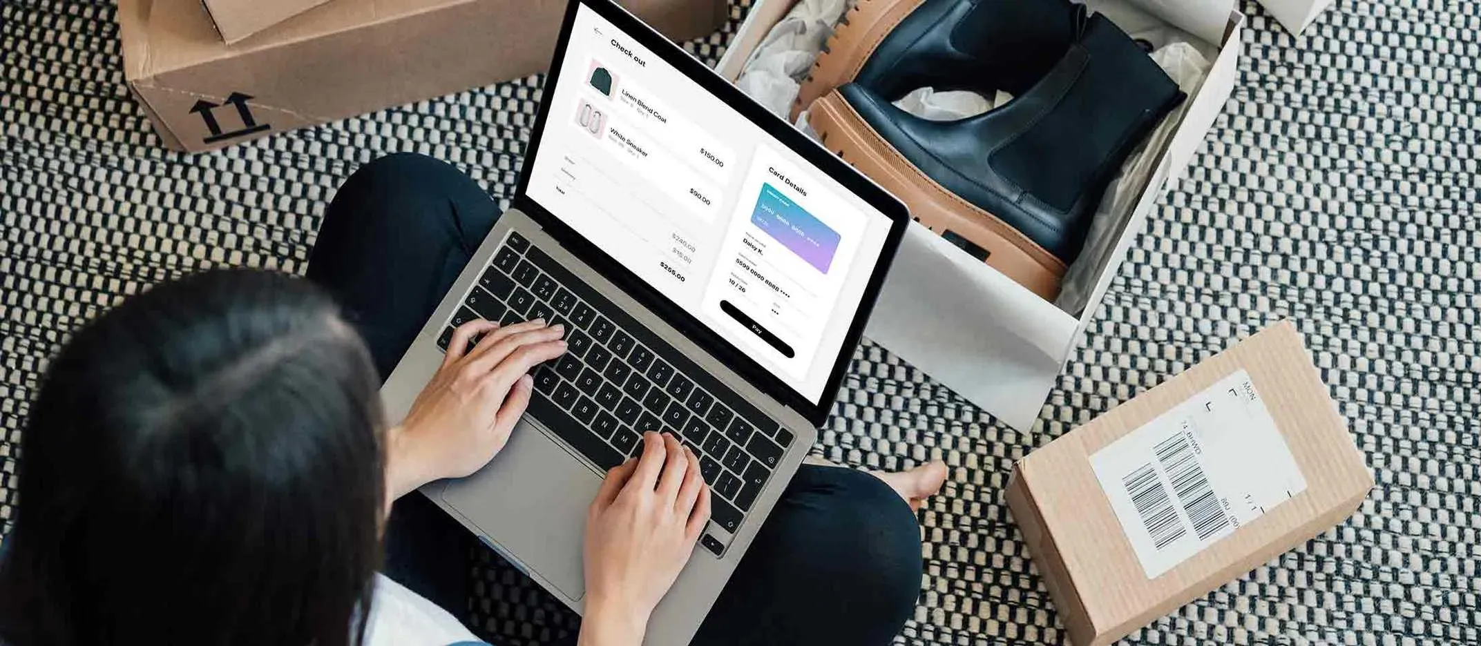 Persona realizando compra en línea desde una laptop, rodeada de cajas y zapatos nuevos.