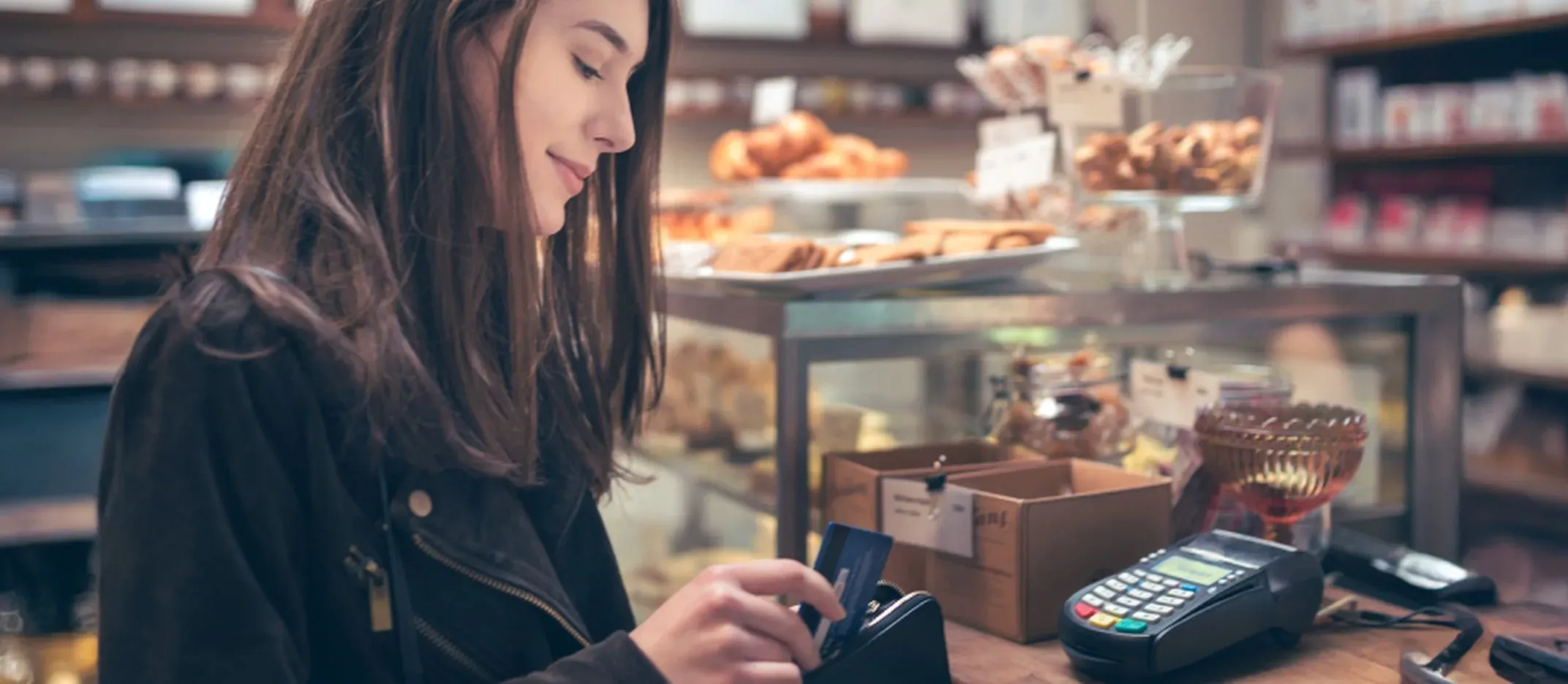 Persona pagando con tarjeta de crédito en una tienda con terminal de pago.
