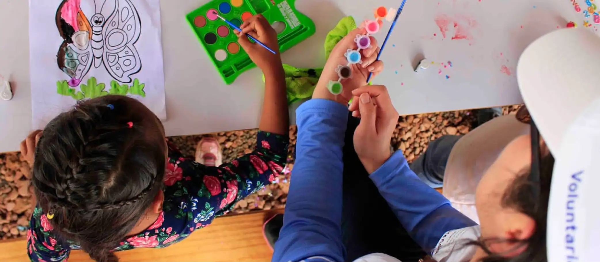 Voluntarios pintan una ilustración de mariposa con pinceles y acuarelas en una actividad de Voluntariado Banamex