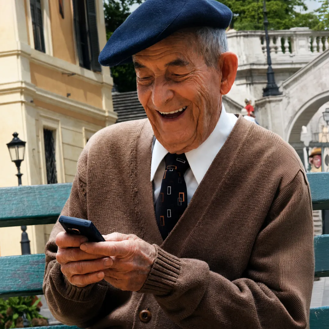 Persona adulta mayor sentada en una banca al aire libre utilizando un teléfono móvil, representando la gestión de servicios digitales y banca móvil Banamex de forma sencilla y segura.