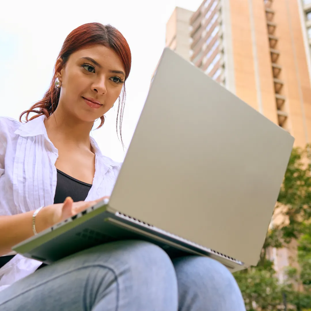 Persona usando una laptop al aire libre, representando el acceso a servicios digitales y la gestión financiera de sus impuestos en línea con Banamex.