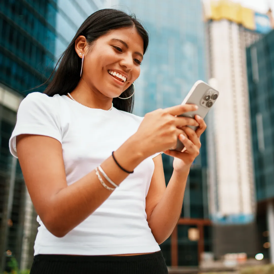 Persona utilizando la app Banamex desde un teléfono móvil en un entorno urbano, para consultar o realizar operaciones financieras digitales.