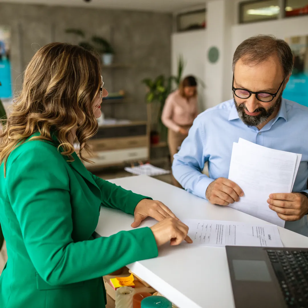 Persona revisando documentos junto a un asesor, evaluando información y opciones para tomar decisiones financieras informadas.