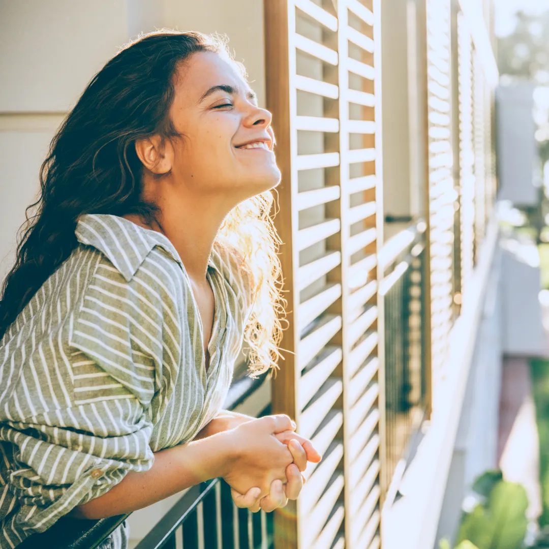 Persona apoyada en un balcón recibiendo la luz del sol, representando bienestar, tranquilidad y la confianza de contar con soluciones financieras para disfrutar cada etapa de la vida con Banamex.