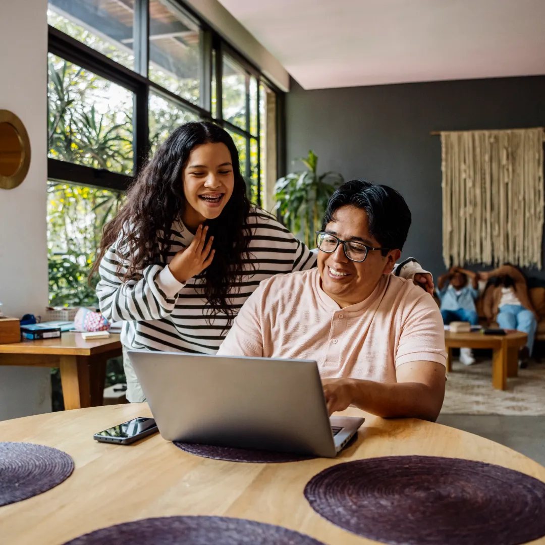 Dos personas consultando información en una laptop desde casa, representando la planificación financiera, la educación digital y la gestión de productos y servicios Banamex.