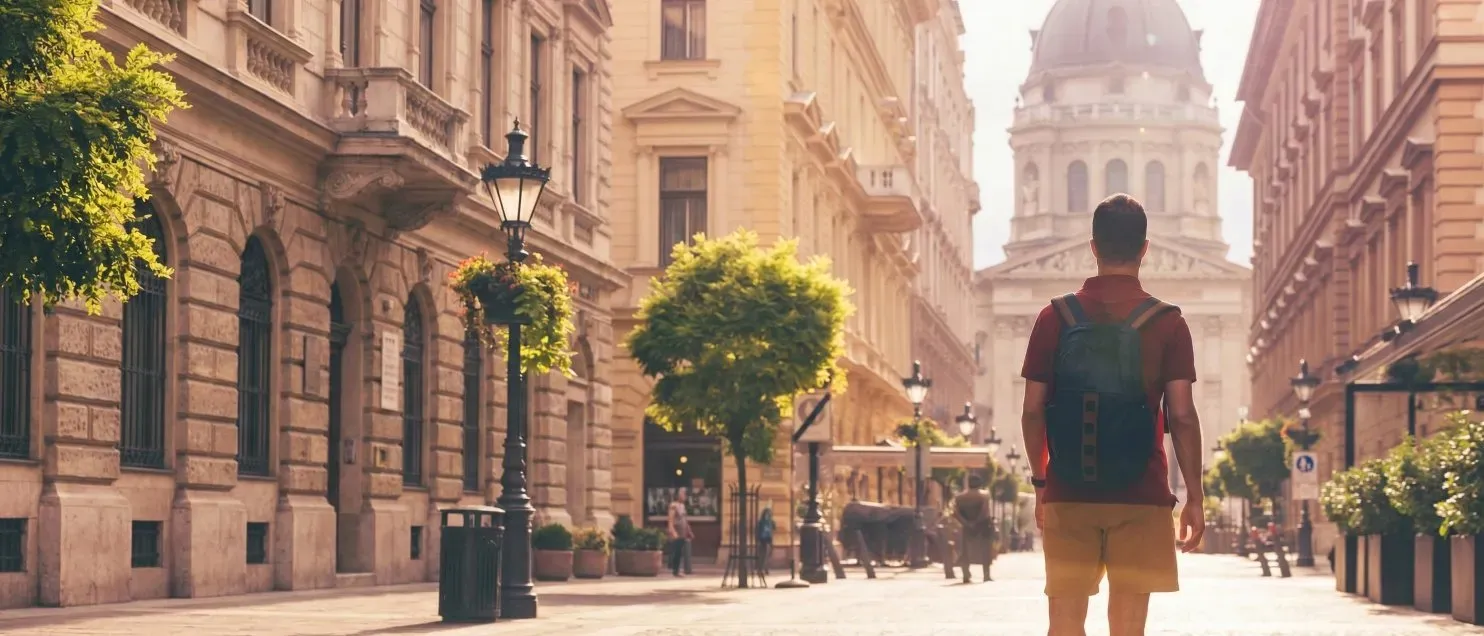 Un hombre usando una mochila caminando por una calle histórica con edificios y catedral.