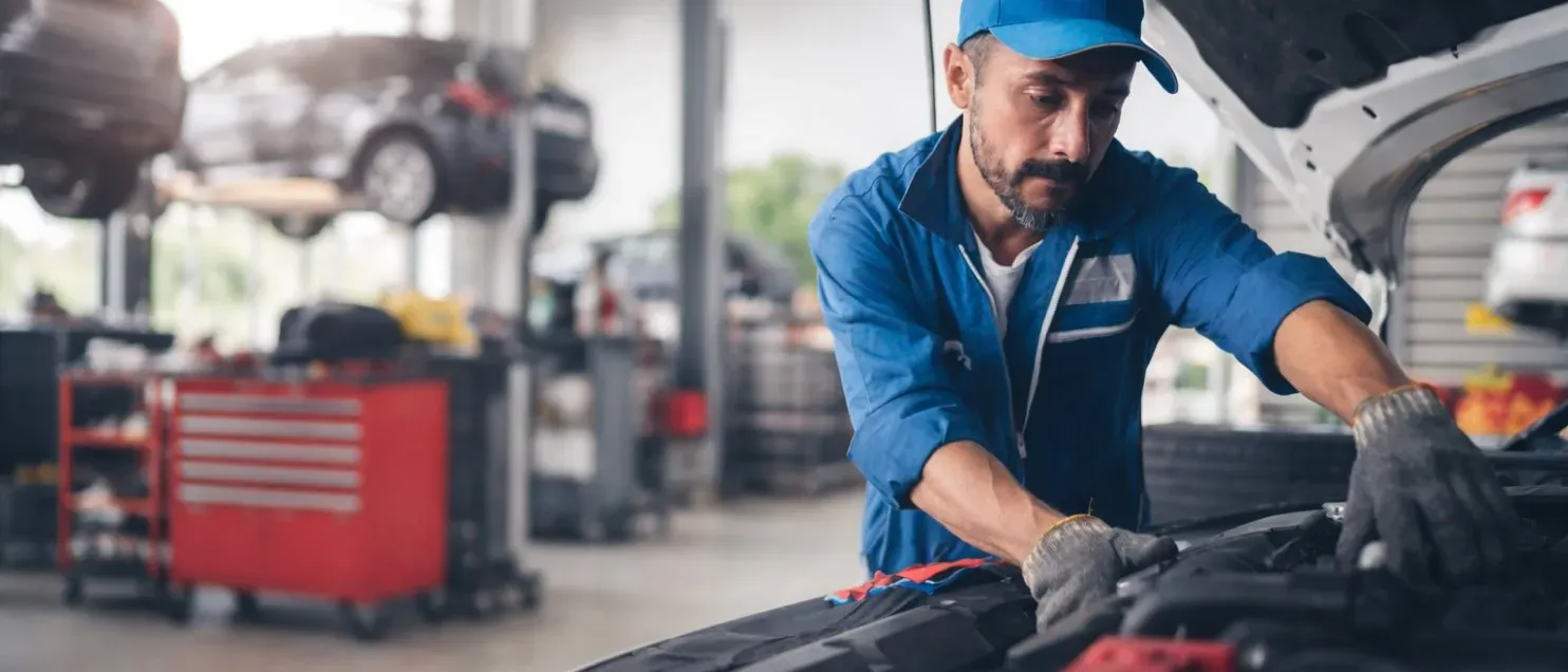 Un mecánico revisando el motor de un automóvil en un taller mecánico.