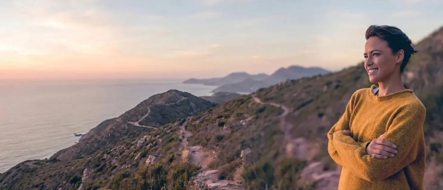 Persona de pie en entorno natural con paisaje montañoso, simbolizando libertad financiera y seguridad para el retiro.