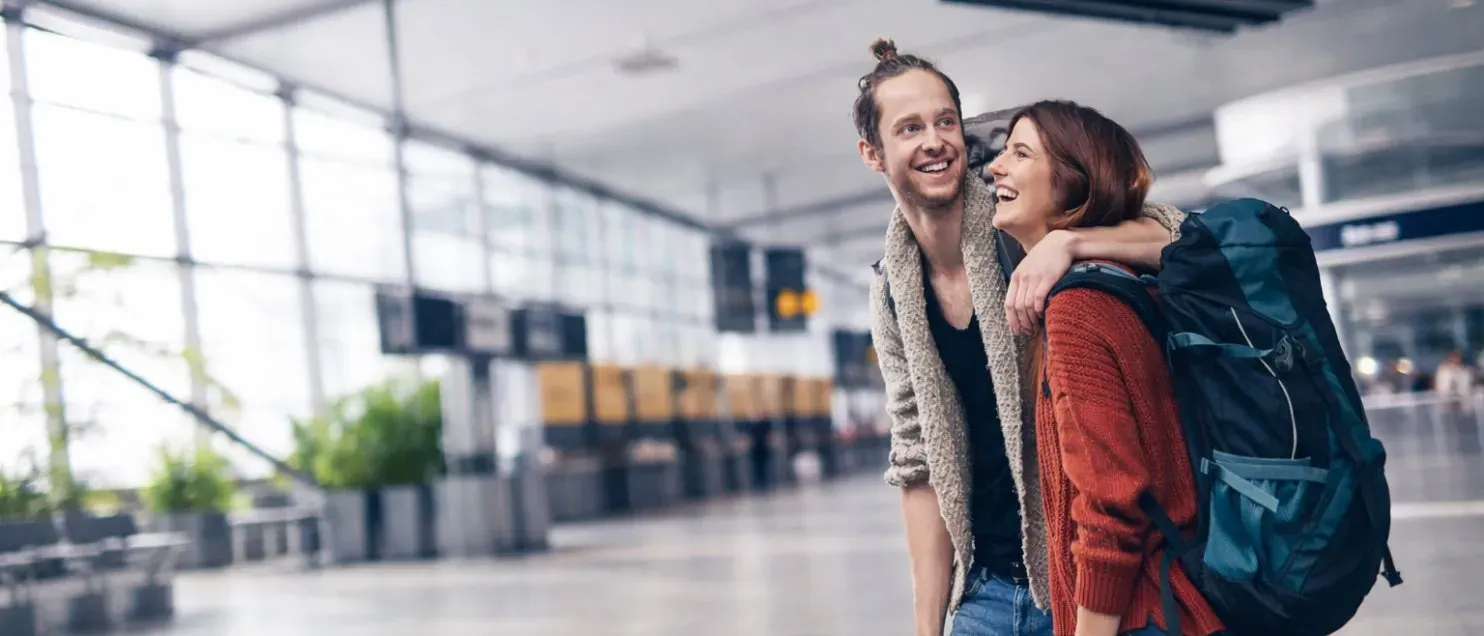 Una pareja usando mochilas caminando en un aeropuerto.