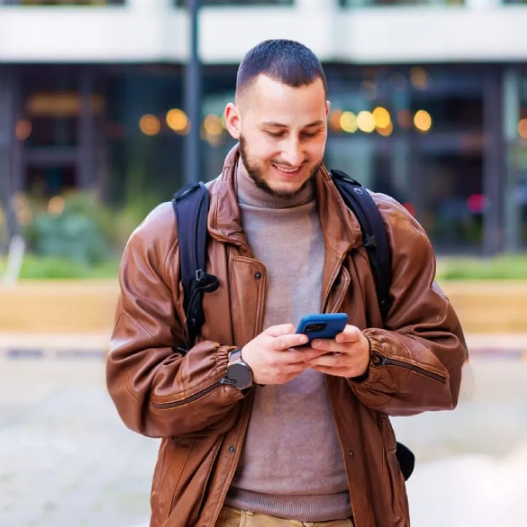 Persona utilizando un teléfono móvil en un entorno urbano, representando el acceso rápido y seguro a servicios financieros, pagos digitales y banca móvil Banamex desde cualquier lugar.