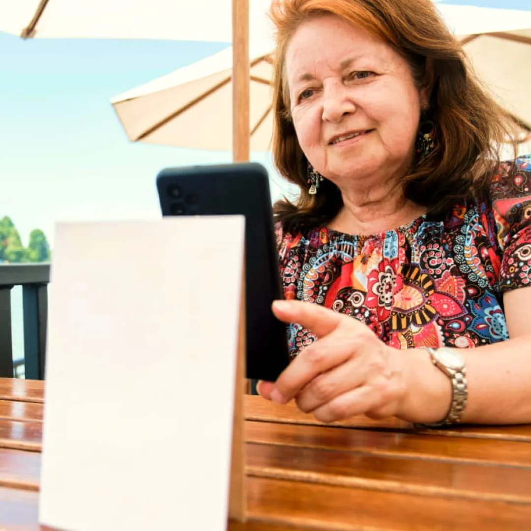 Persona adulta utilizando un teléfono móvil mientras se encuentra al aire libre, representando el acceso sencillo y seguro a servicios financieros digitales y banca móvil Banamex desde cualquier lugar.