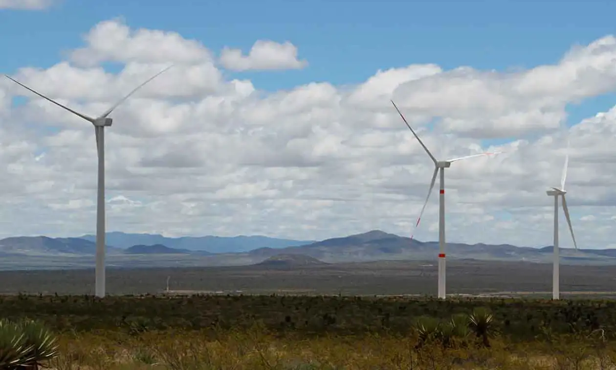Tres aerogeneradores en campo abierto con colinas al fondo, energía renovable de la estrategia ASG de Banamex