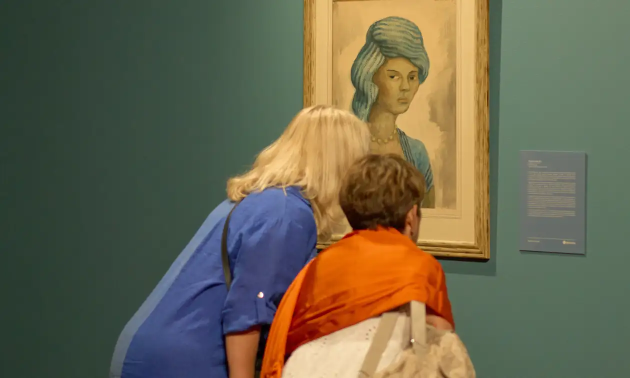 Visitantes observan un retrato de mujer con vestimenta azul en una galería de arte de Fomento Cultural Banamex