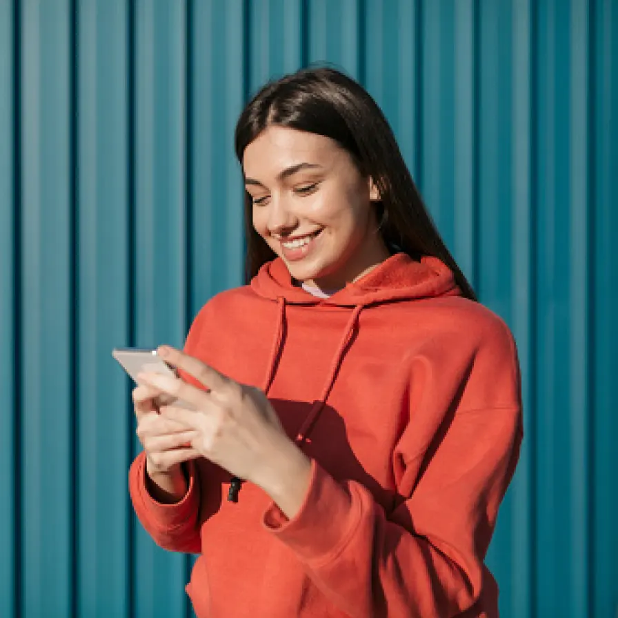 Persona utilizando un teléfono móvil frente a un fondo azul, consultando información y gestionando servicios digitales desde su dispositivo.