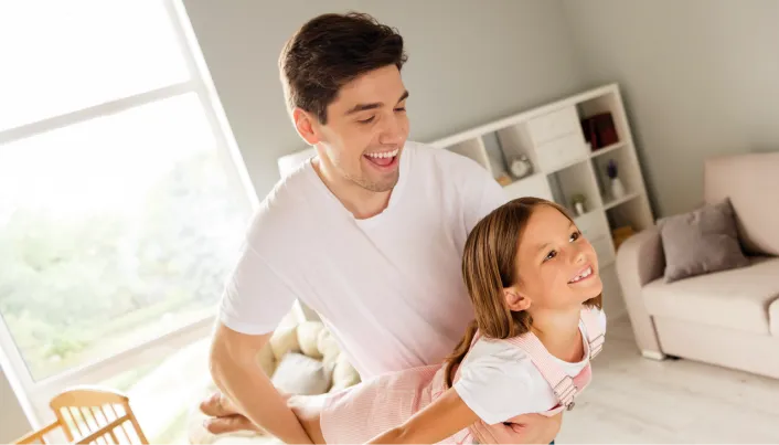 Persona y menor de edad compartiendo tiempo en el hogar, representando bienestar familiar, protección financiera y planificación para el futuro de las familias.
