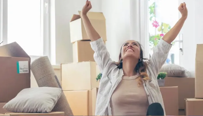 Persona celebrando una mudanza en un nuevo hogar, representando metas patrimoniales, compra de vivienda y estabilidad financiera para proyectos de vida a largo plazo.