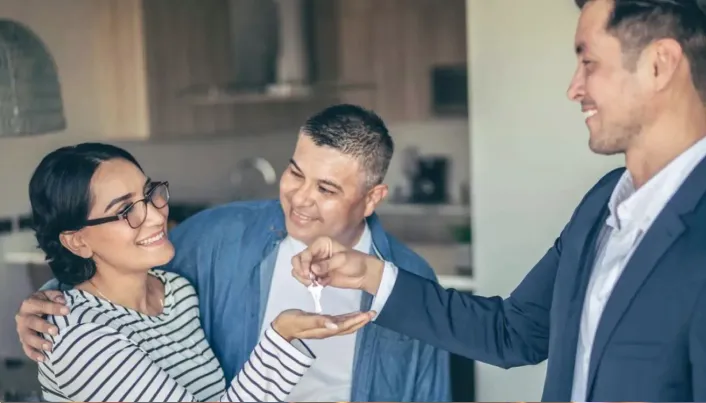 Entrega de llaves de una vivienda durante el proceso de compra o adquisición de un inmueble, representando el logro de metas patrimoniales, financiamiento y acceso a un nuevo hogar.