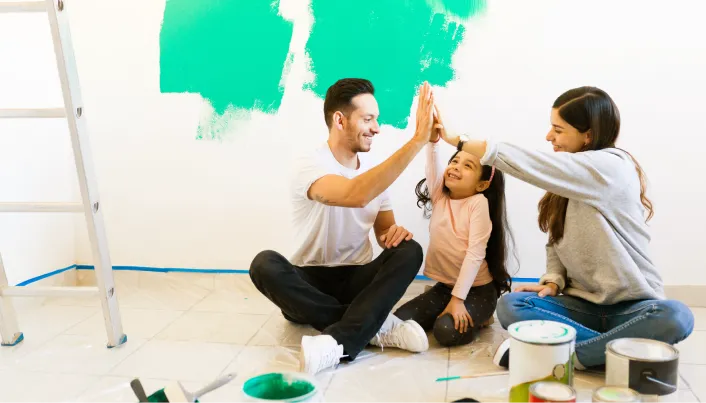 Familia realizando mejoras en el hogar, representando proyectos de vivienda, remodelación, bienestar familiar y planificación financiera para alcanzar metas patrimoniales.
