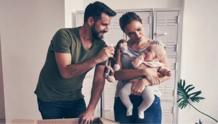 Familia con un bebé organizando pertenencias en una vivienda, durante una mudanza o el proceso de instalación en un nuevo hogar.