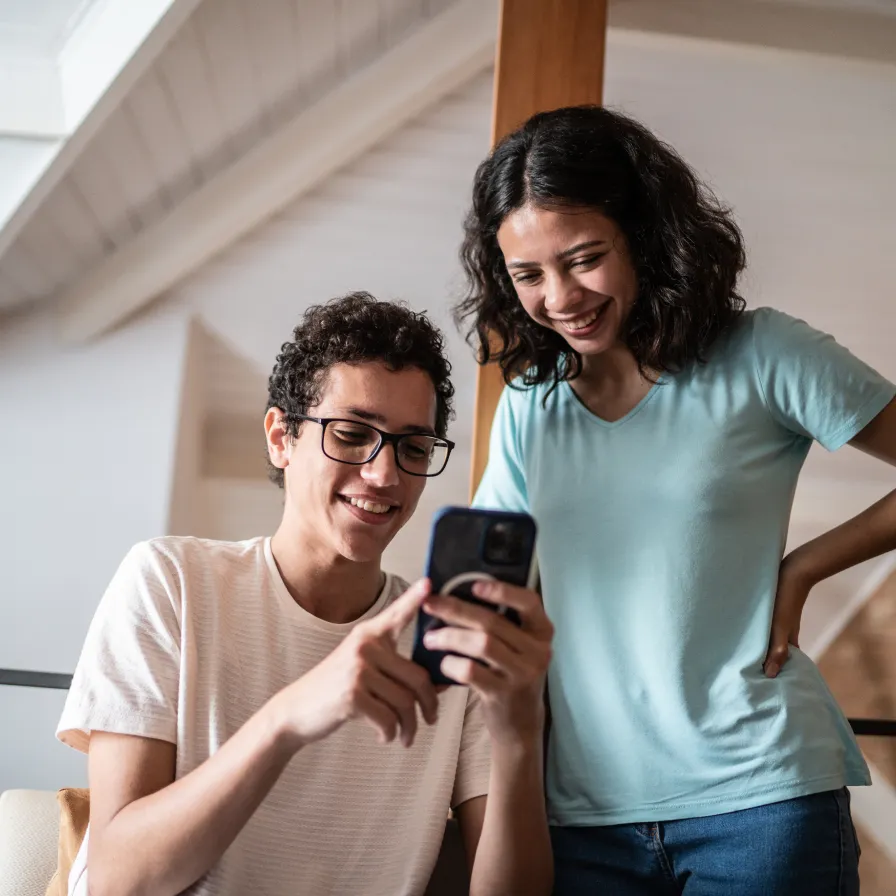 Dos personas consultando un teléfono móvil desde casa, representando el uso de servicios digitales y la banca móvil de Banamex.