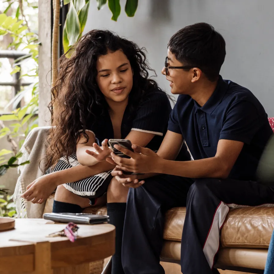 Dos personas consultando un teléfono móvil desde casa, representando el acceso a servicios digitales y gestión financiera con Banamex.
