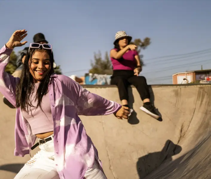 Persona disfrutando una actividad recreativa en una pista de patinaje, acompañada de otras personas en un entorno al aire libre.