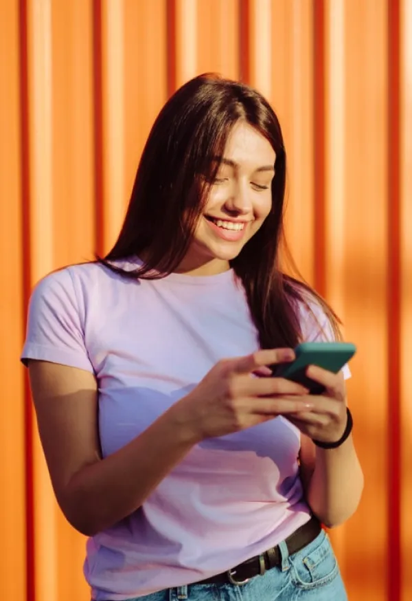 Una mujer feliz revisando su celular.