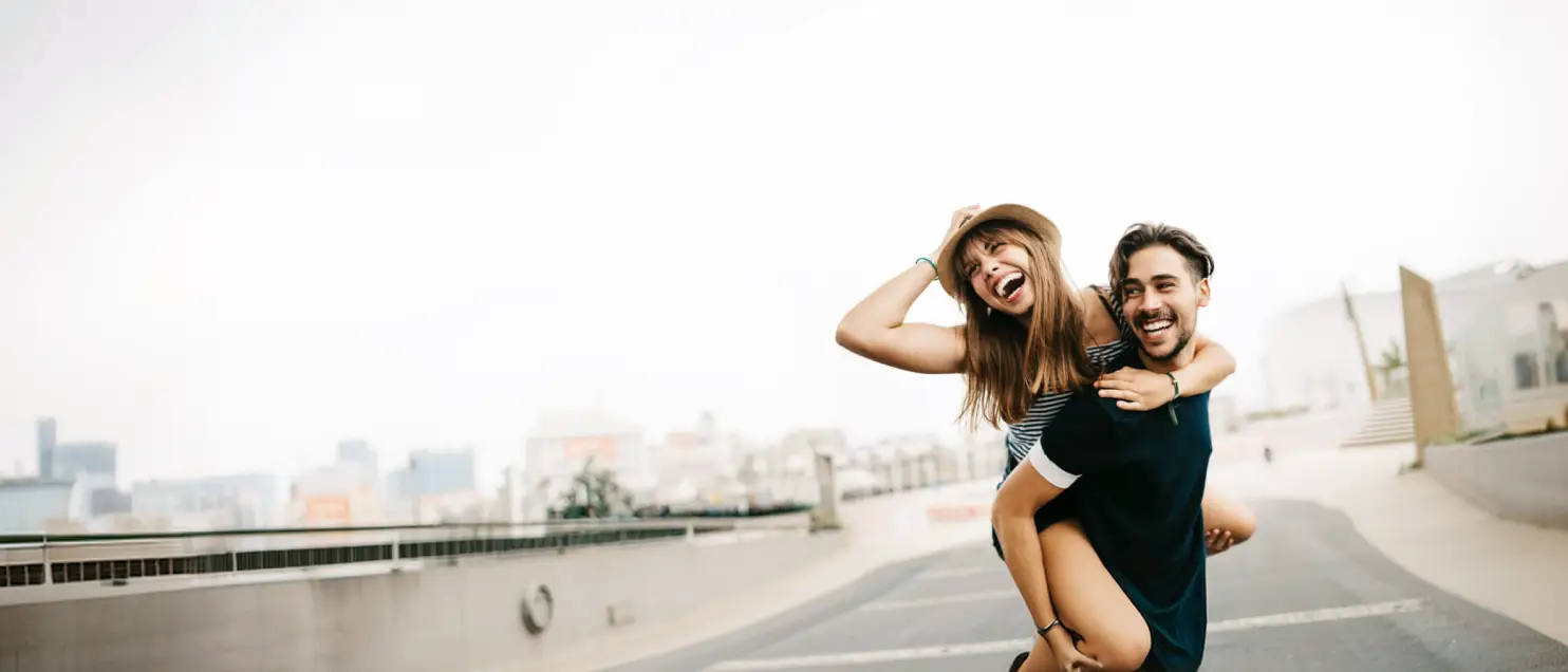 Pareja compartiendo un momento de diversión al aire libre en un entorno urbano, reflejando experiencias, bienestar y estilo de vida.