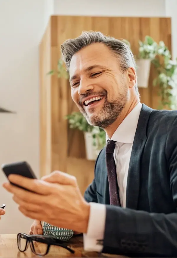 Persona usando un teléfono móvil durante una reunión en una oficina, representando la gestión de servicios financieros digitales Banamex.