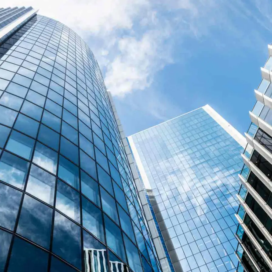 Edificios corporativos con fachadas de cristal reflejando el cielo, representando solidez, innovación y servicios empresariales de Banamex.