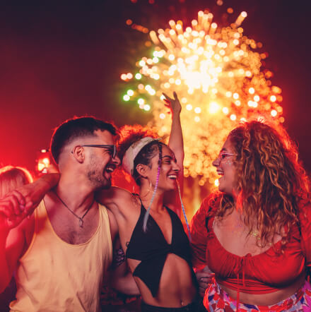 Personas disfrutando de un festival al aire libre con espectáculo de fuegos artificiales y actividades de entretenimiento en vivo.
