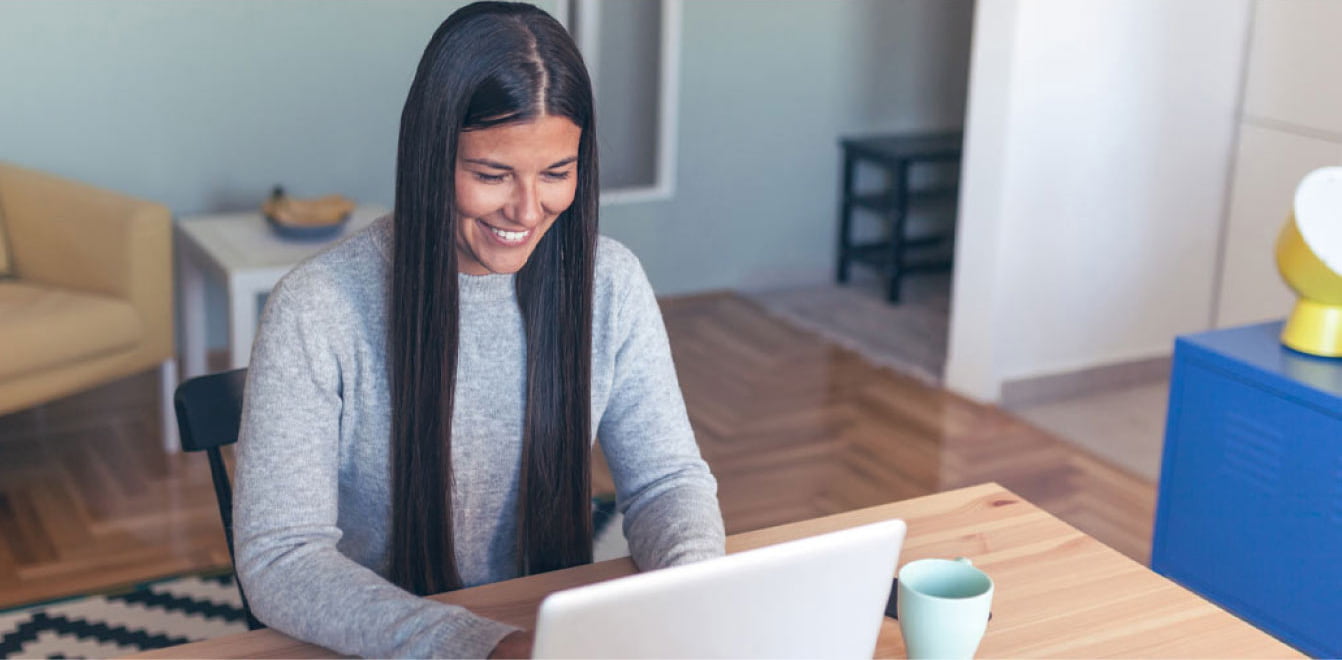 Persona utilizando una computadora portátil desde casa para gestionar trámites, consultar información y administrar sus finanzas digitales.