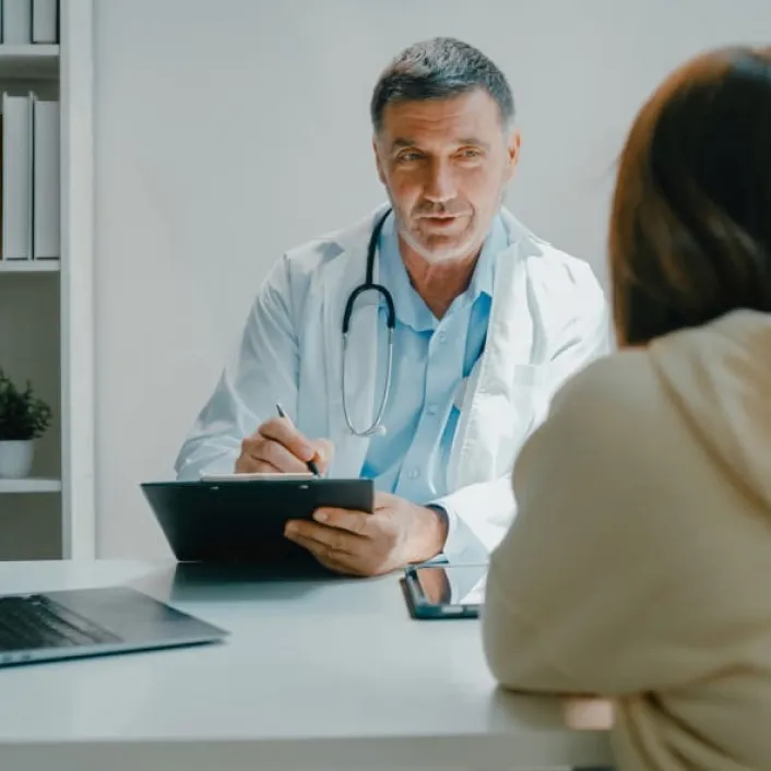 Profesional de la salud brindando orientación médica durante una consulta, revisando información clínica y resolviendo dudas de la persona atendida.