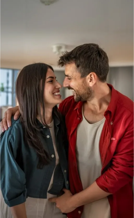 Pareja compartiendo un momento en su hogar, reflejando bienestar, estabilidad financiera y proyectos de vida en común.
