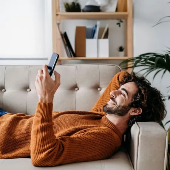 Joven revisando en su celular los pagos guardados con su Tarjeta Banamex.