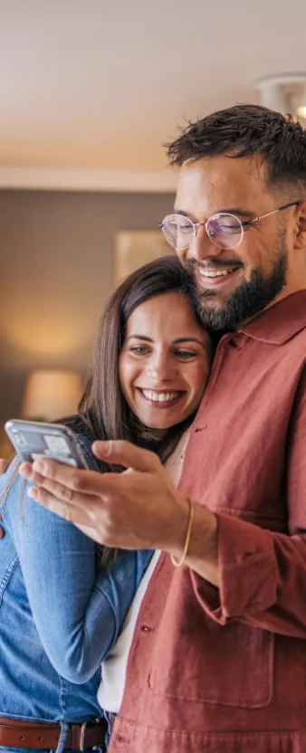 Una pareja abrazada mientras revisan su celular.