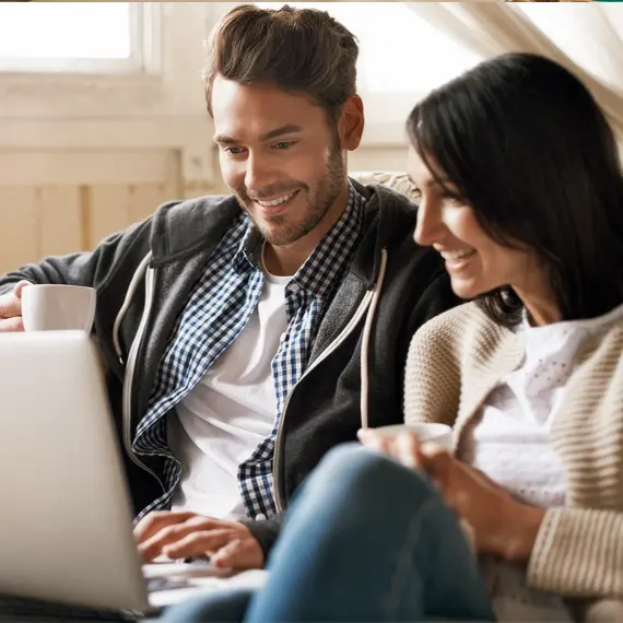 Pareja revisando información financiera desde una computadora portátil en casa para planificar metas y tomar decisiones patrimoniales.