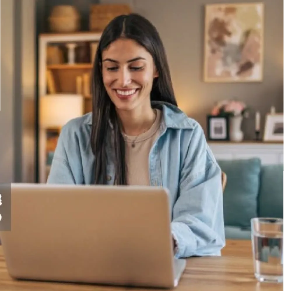 Una mujer usando su laptop en mesa dentro de una oficina.