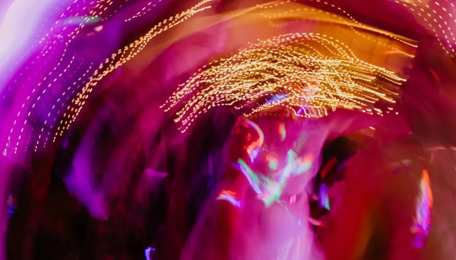 Luces de colores en movimiento creando efecto abstracto en entorno de evento nocturno.
