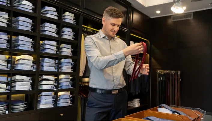 Persona seleccionando accesorios en una tienda de ropa formal.
