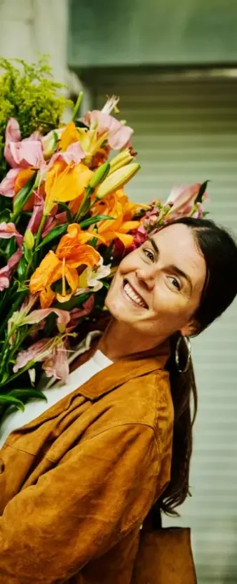 Una mujer sonriendo sosteniendo un gran ramo de flores.