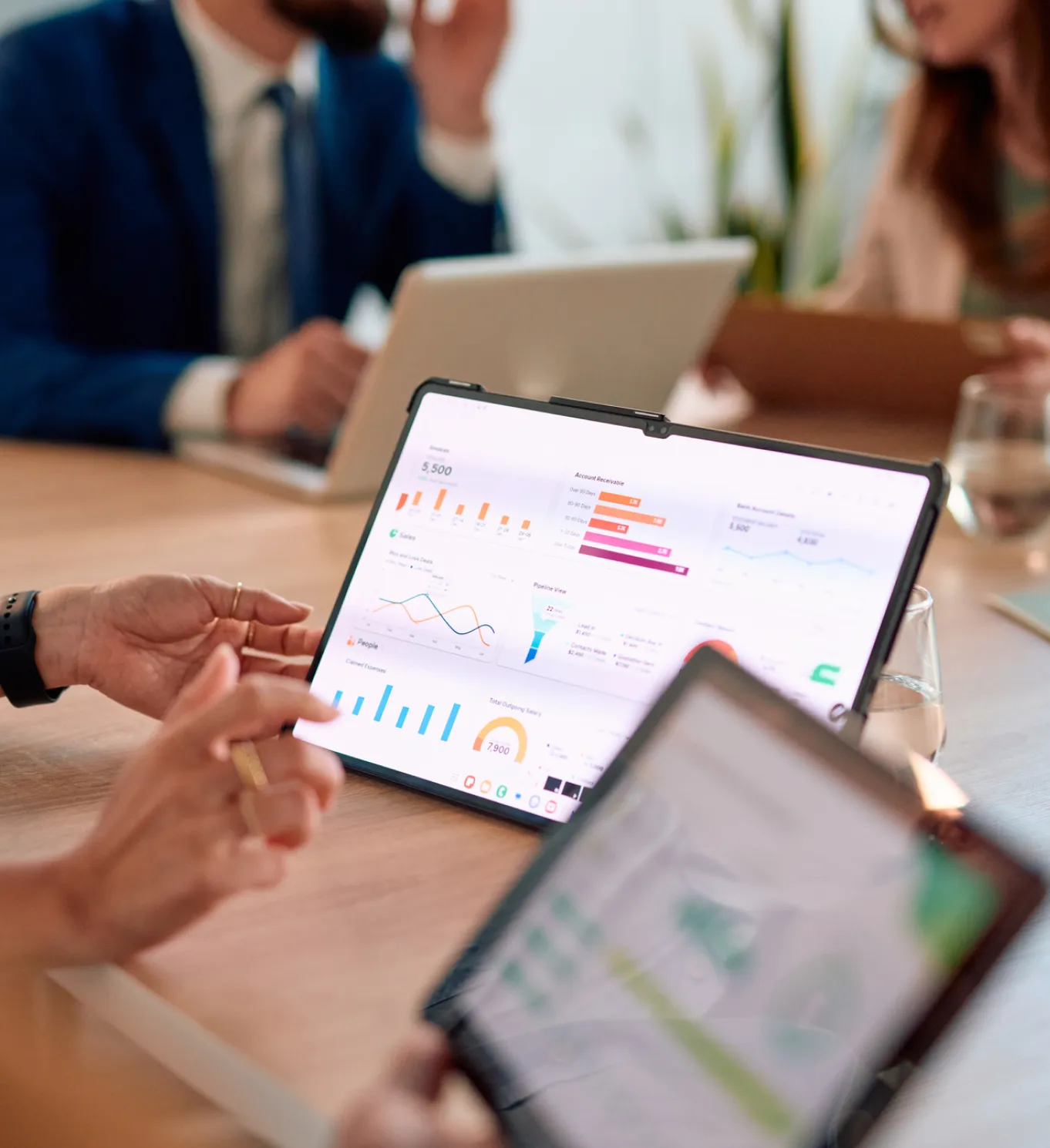 Personas revisando indicadores y gráficos financieros en una tablet durante una reunión de análisis y planeación estratégica.