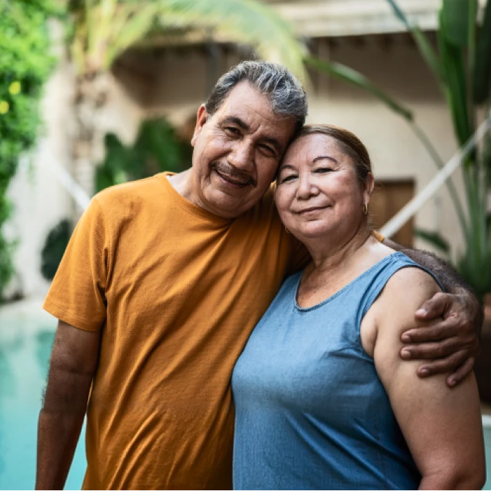 Pareja disfrutando tiempo juntos frente a su vivienda, reflejando tranquilidad, protección patrimonial y bienestar familiar.